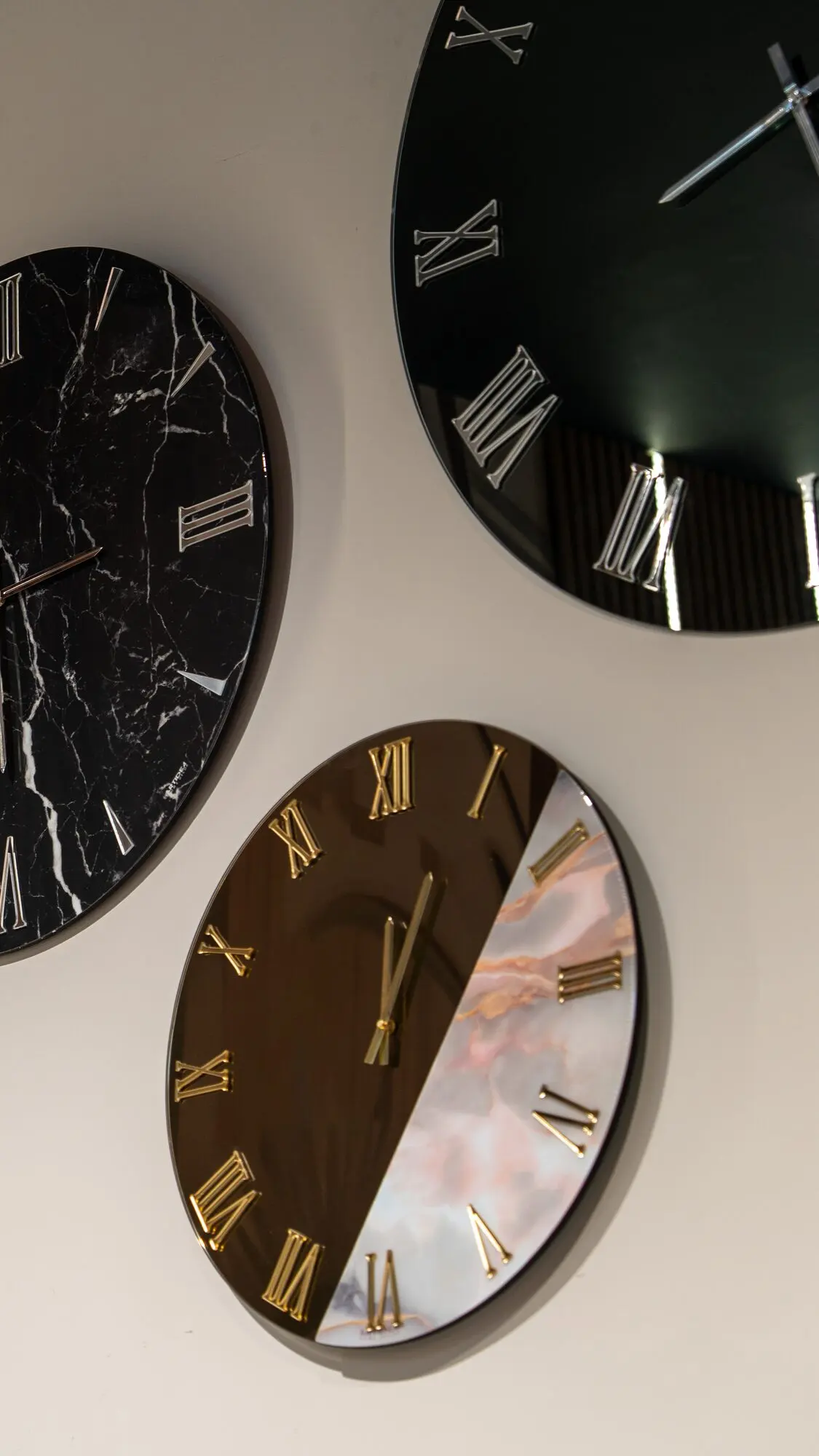 Tre orologi da parete di grandi dimensioni, con quadrante effetto marmo e numeri romani dorati.